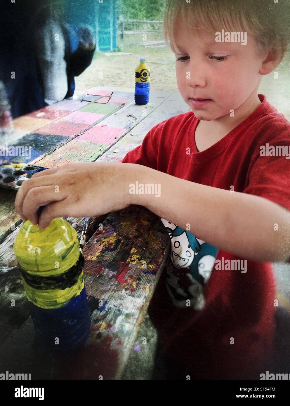 A boy paints a plastic bottle, making a craft. - Smartphone Captured Stock Image