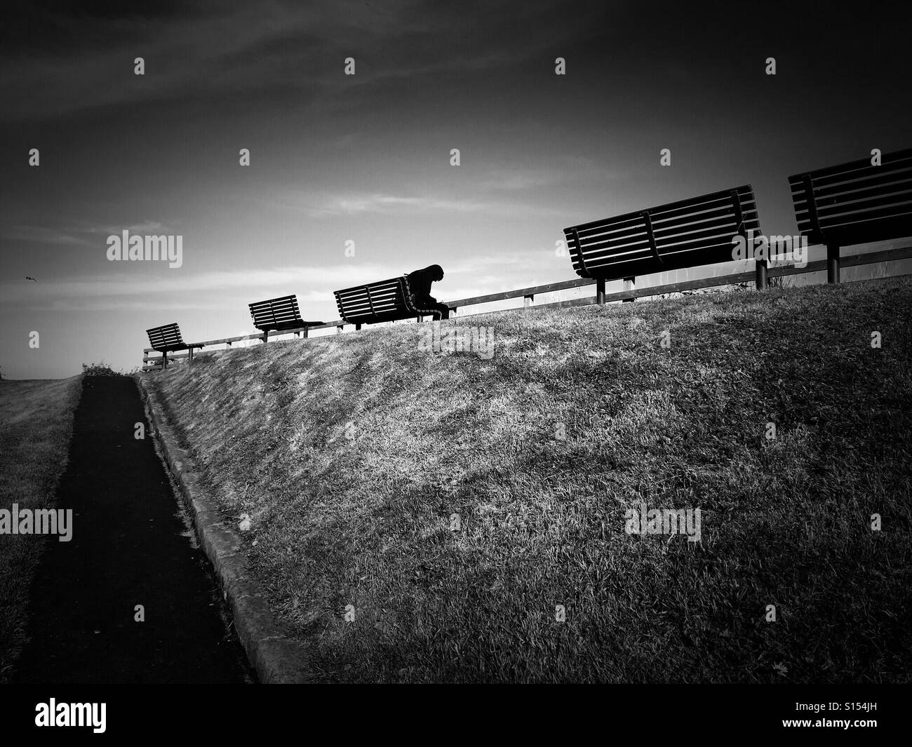 Hunched figure on a bench on a clifftop - Smartphone Captured Stock Image