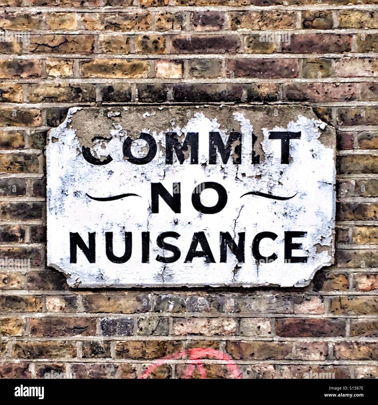Commit no nuisance sign on brick wall Stock Photo