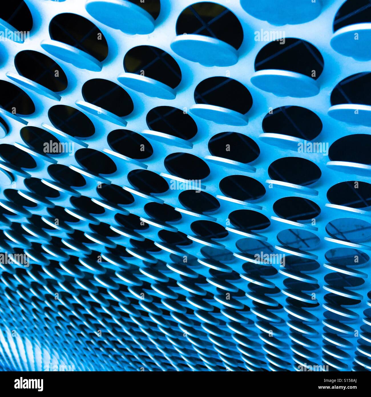 A detail of a wall with circular tabs bent out at different angles. - Smartphone Captured Stock Image