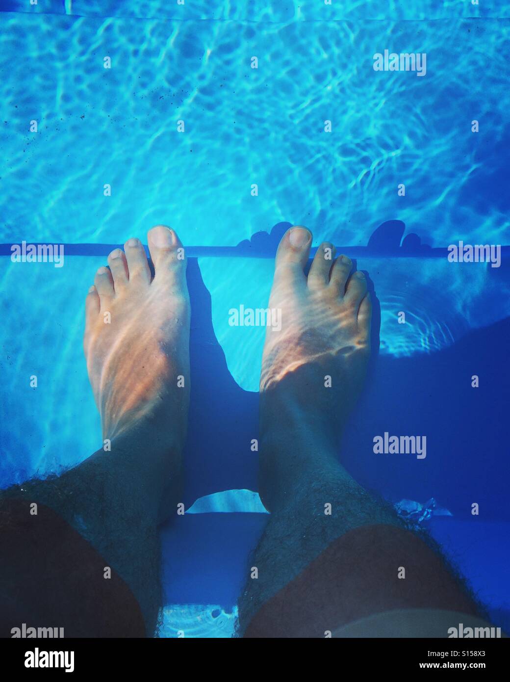 A pair of feet cooling in a swimming pool - Smartphone Captured Stock Image