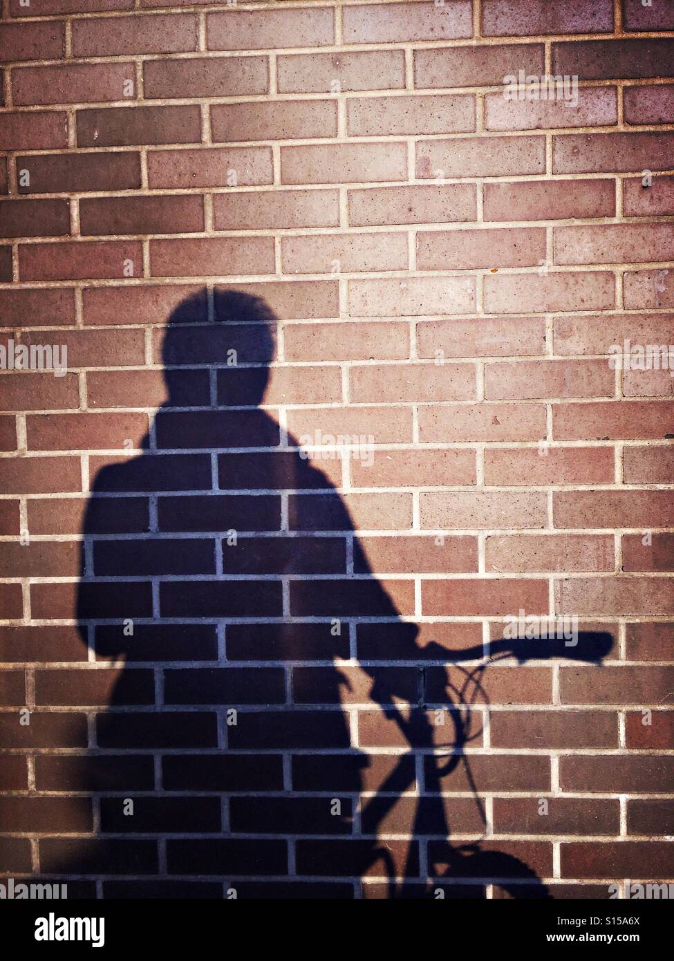 Shadow of a cyclist against a brick wall Stock Photo