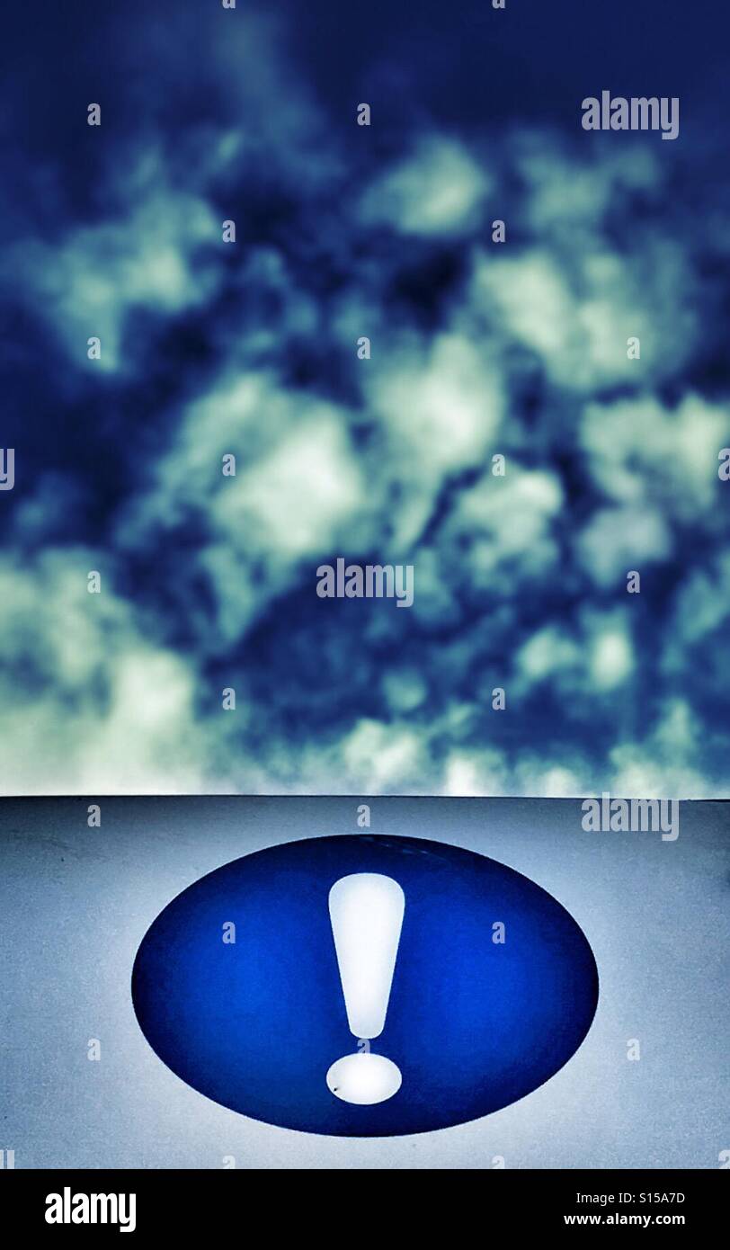 White exclamation mark in blue circle against a cloudy blue sky - Smartphone Captured Stock Image