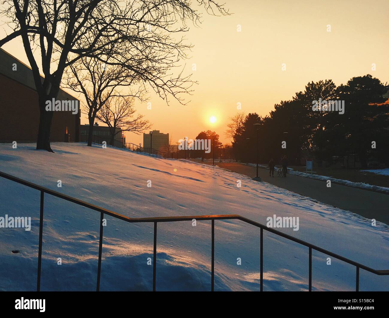 The sun sets over a snowy college campus. Stock Photo