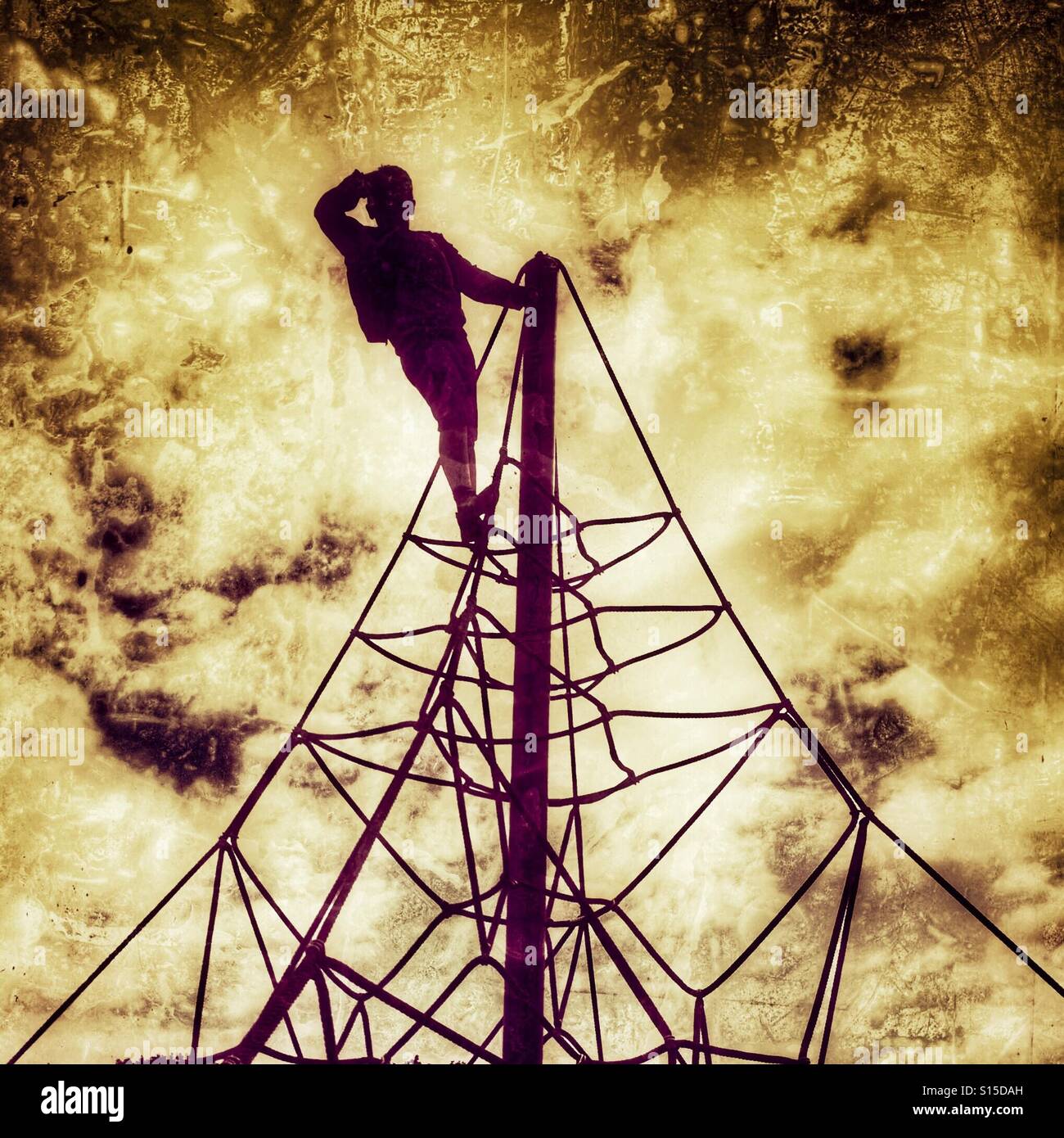 Young boy at  the top of playground climbing apparatus Stock Photo