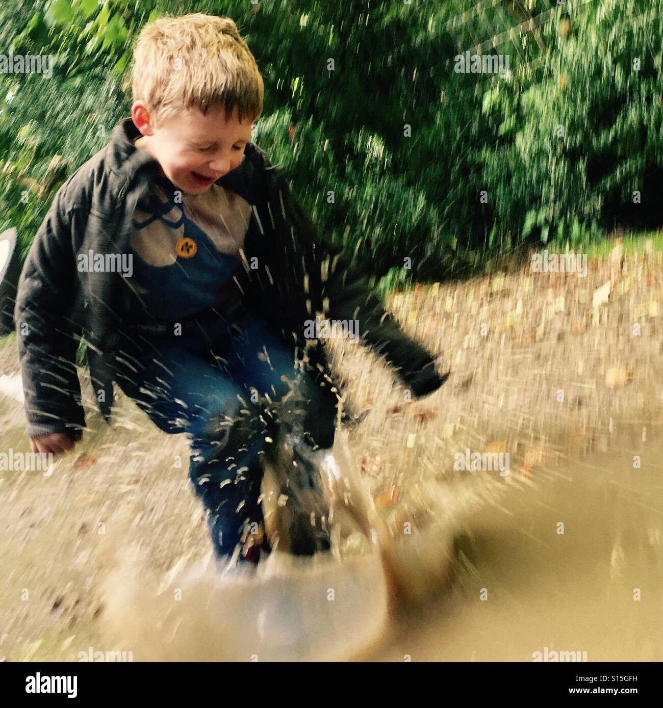 Four year old boy splashing in a muddy puddle - Smartphone Captured Stock Image