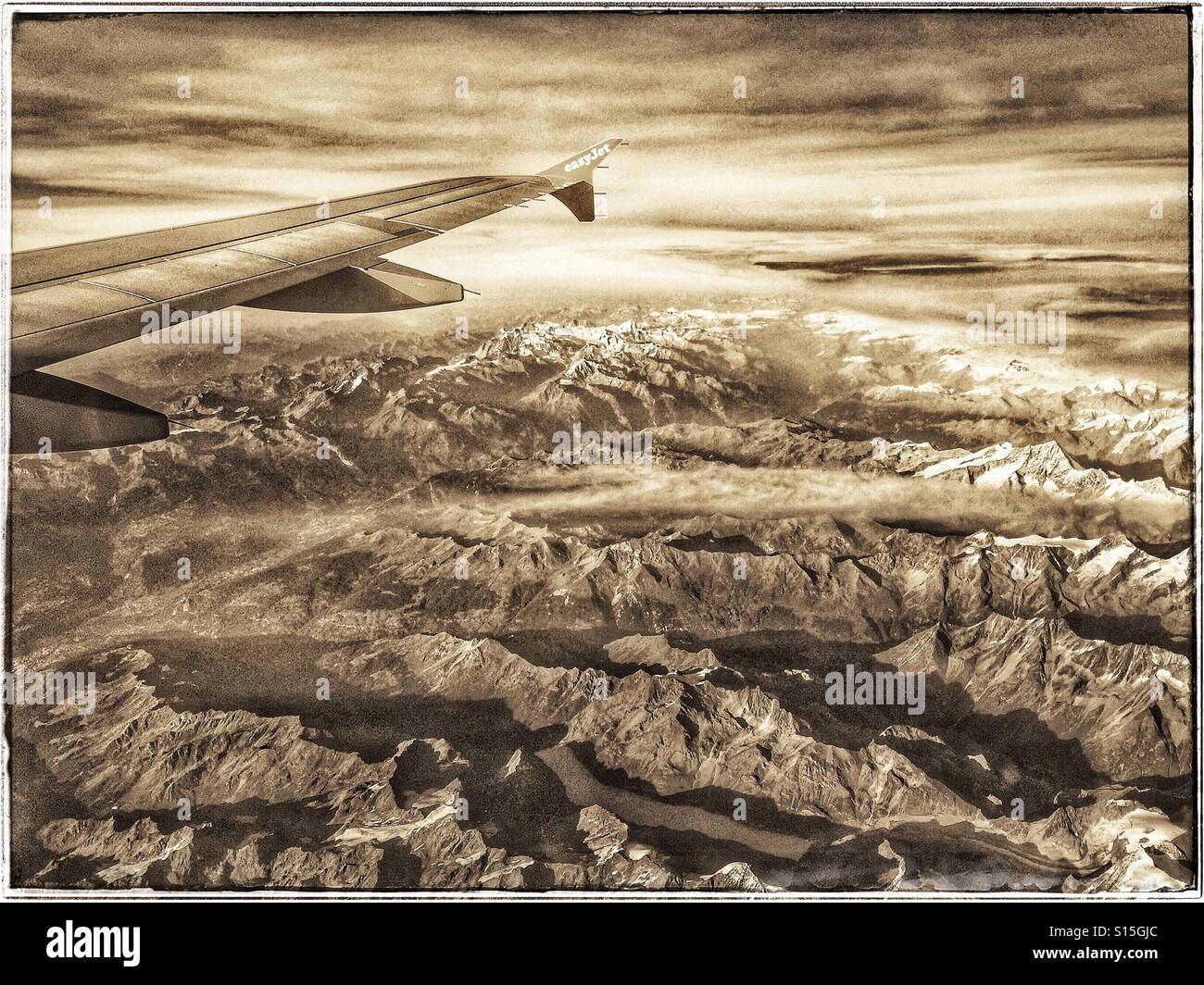A retro, sepia effect, image of the view out of an aircraft window as it flies over The Alps mountain range in Switzerland. Photo Credit - © COLIN HOSKINS. - Smartphone Captured Stock Image