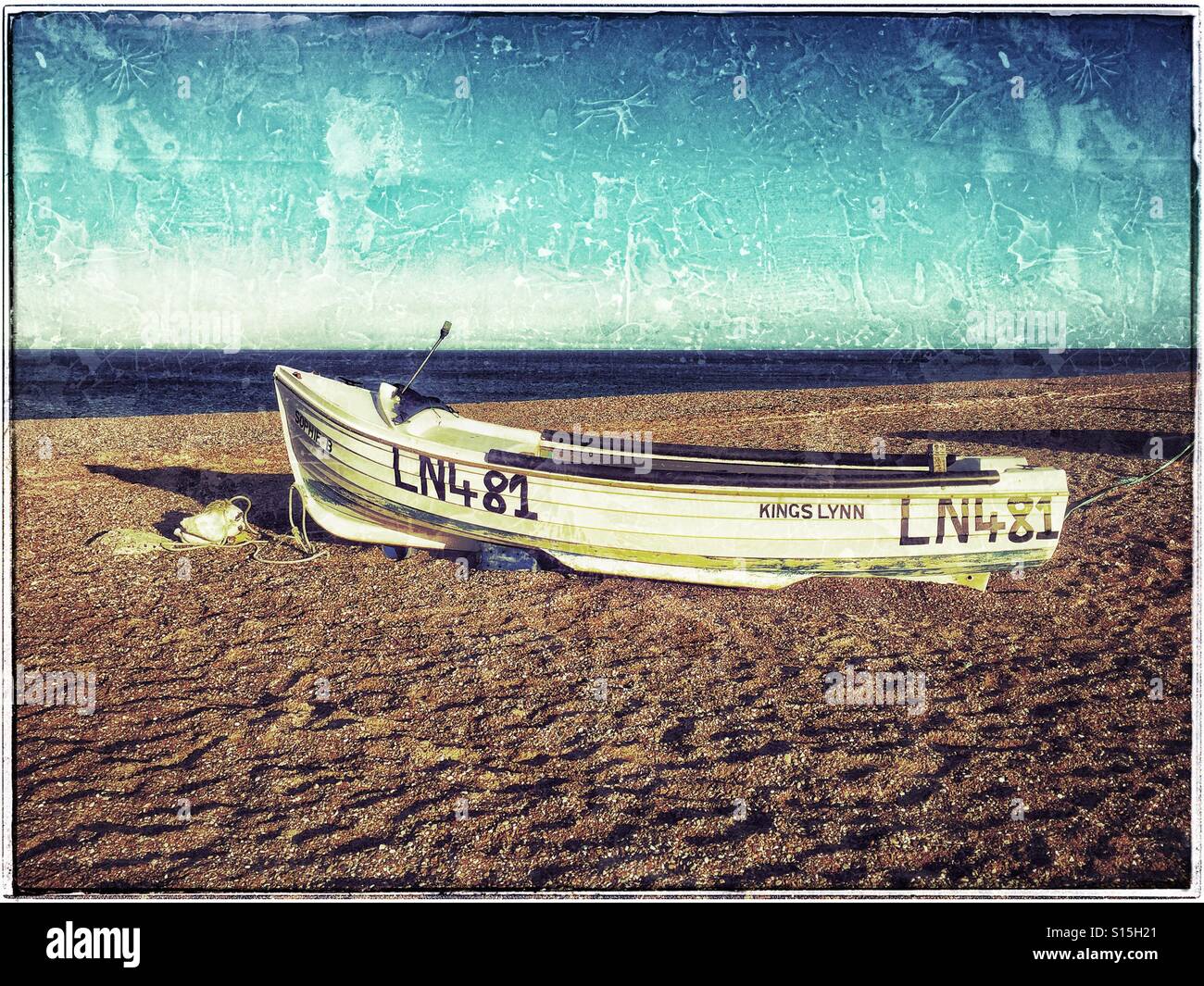 A lonely boat lies on the beach in the Blakeney National Nature Reserve near Cley-next-the-Sea in Norfolk, England. The sea on the horizon is the North Sea. Photo Credit - © COLIN HOSKINS. - Smartphone Captured Stock Image