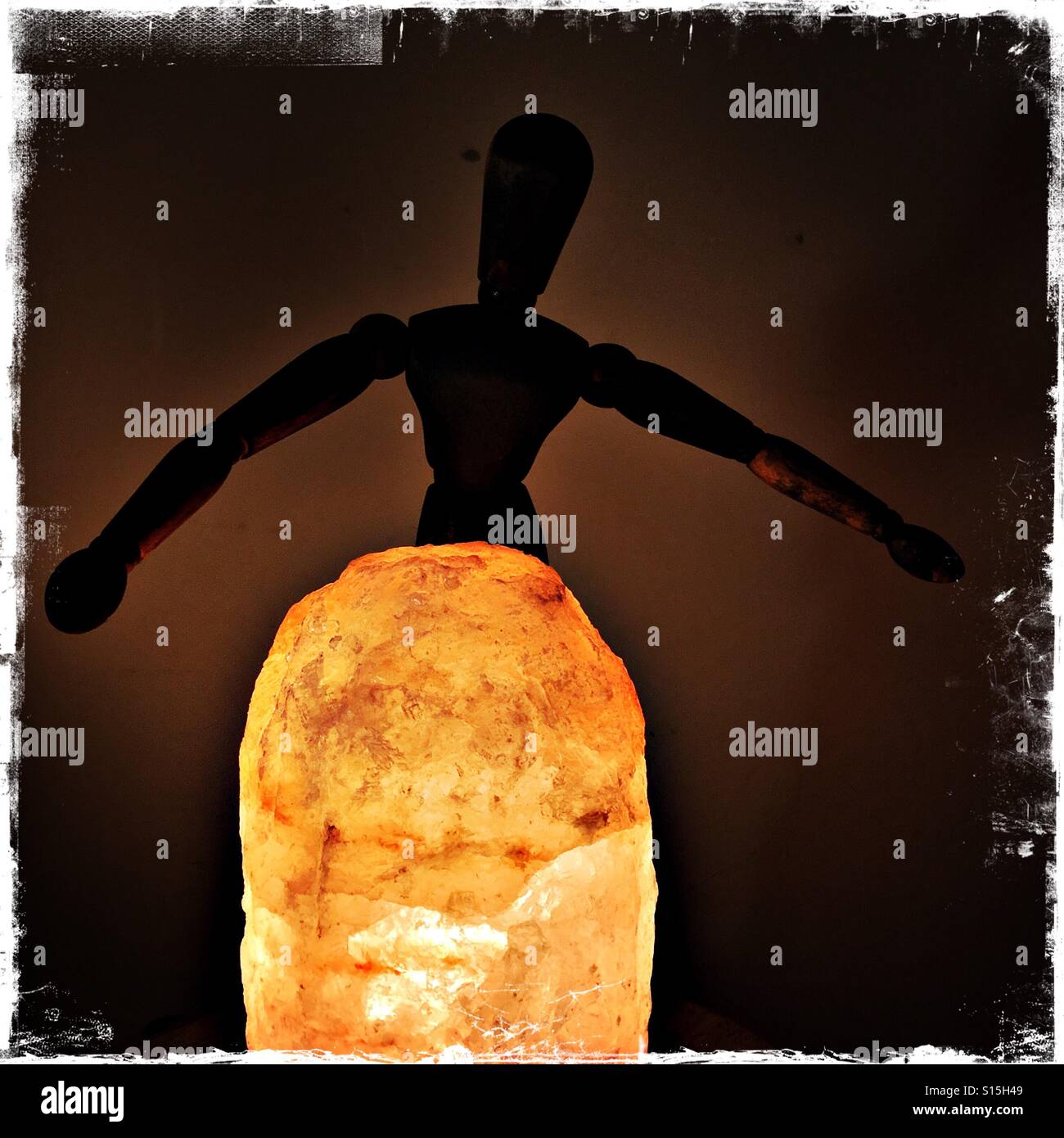 Silhouette of wooden  doll standing behind Himalayan salt lamp - Smartphone Captured Stock Image