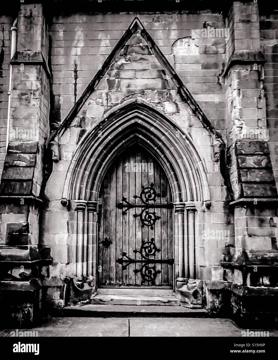 Gothic styled arched doorway to medieval church with wooden door and wrought iron hinges, Scotland, UK - Smartphone Captured Stock Image