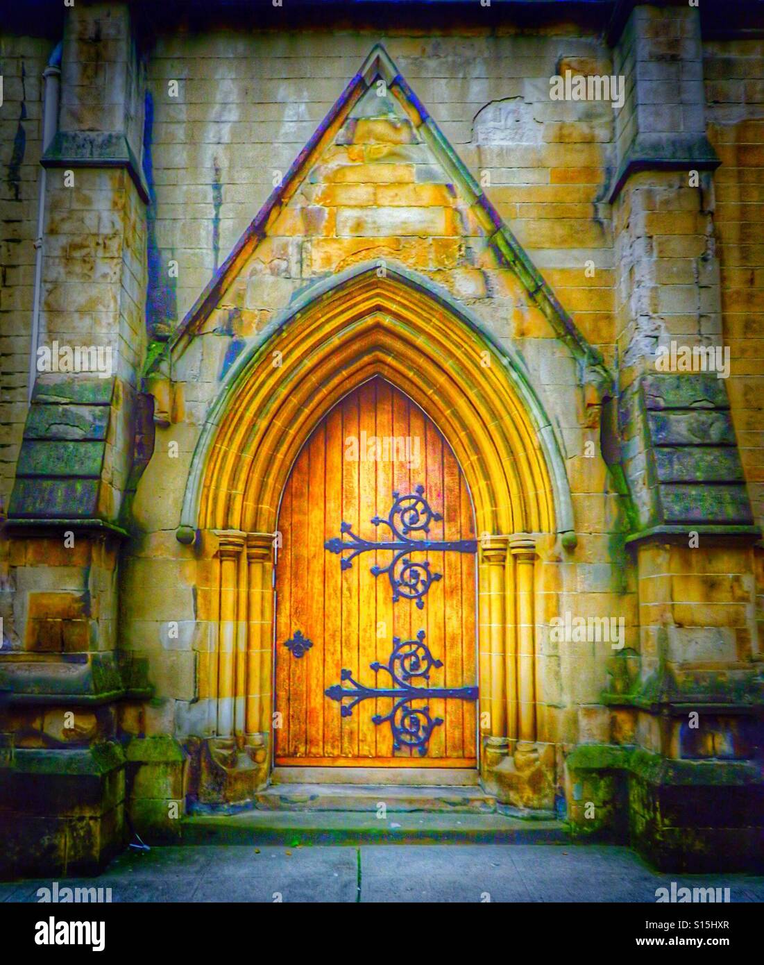 Gothic styled arched doorway to medieval church with wooden door and wrought iron hinges, Scotland, UK - Smartphone Captured Stock Image