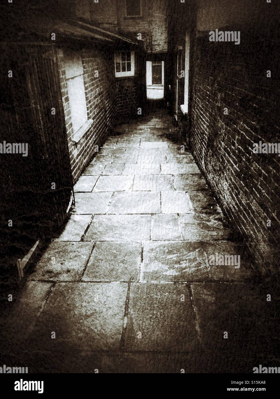 Dark alley, narrow with stone flagged walkway Stock Photo