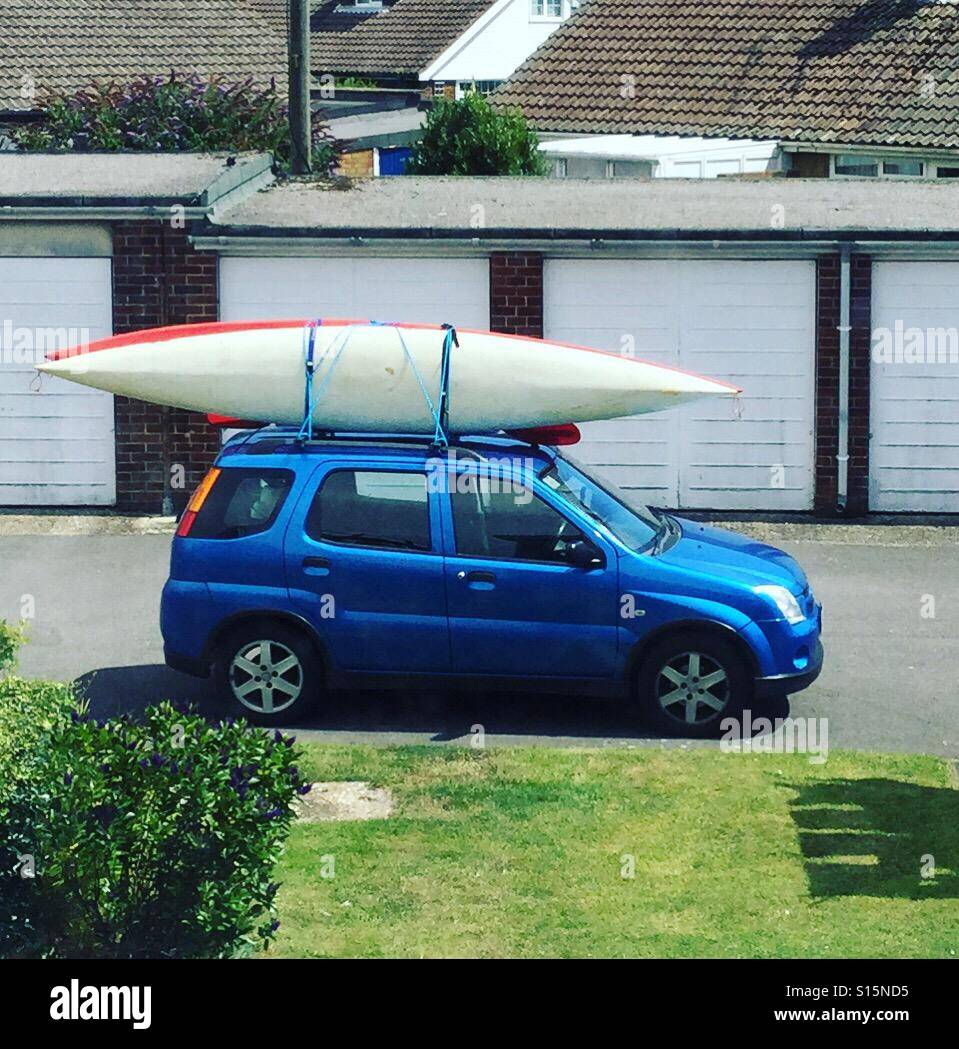 Small Suzuki Ignis with two kayaks on the roof in front of a row of garages  Stock Photo - Alamy