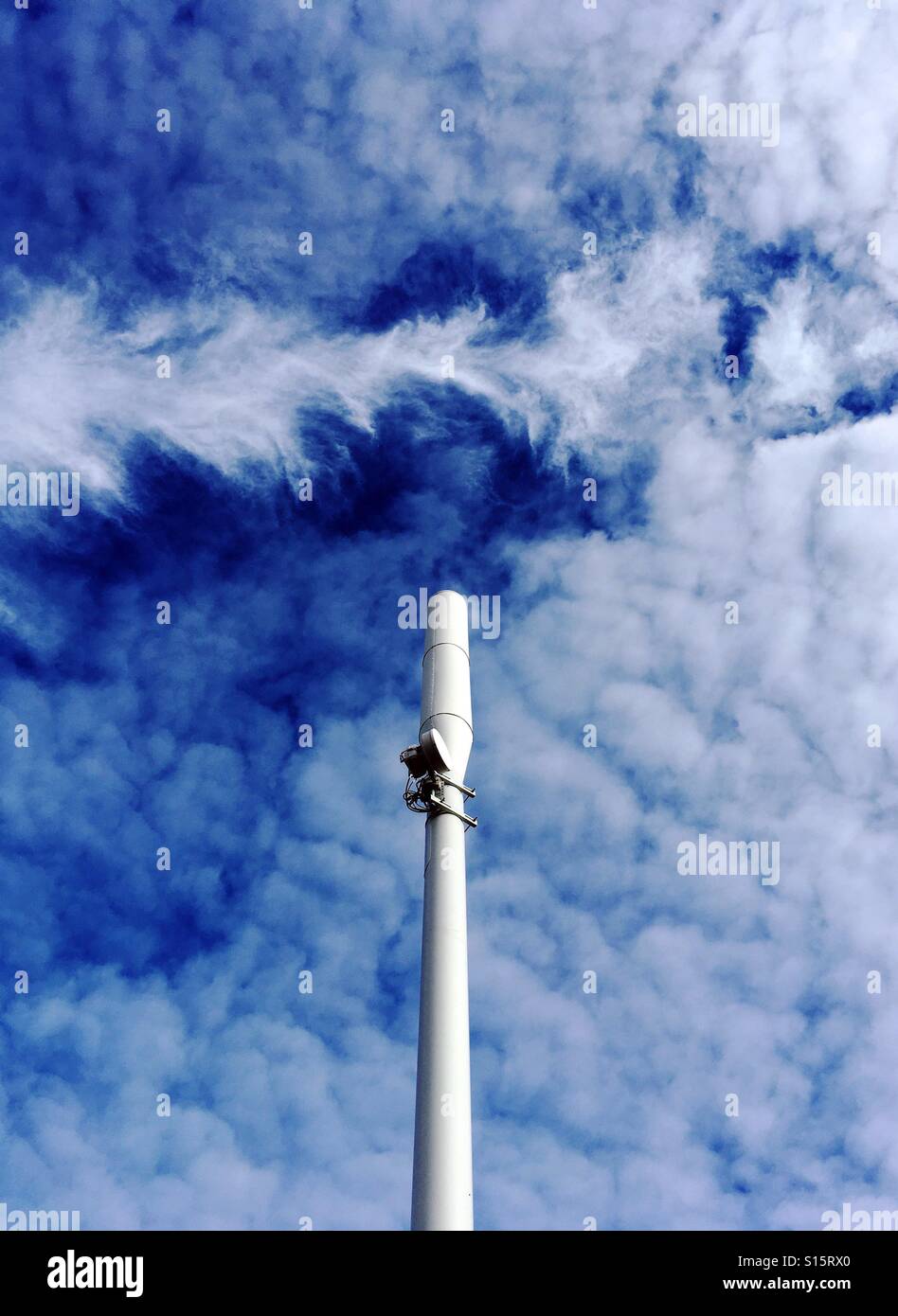 A simulated Kodachrome image of a mobile telephone mast against a background of blue sky and dramatic clouds. - Smartphone Captured Stock Image
