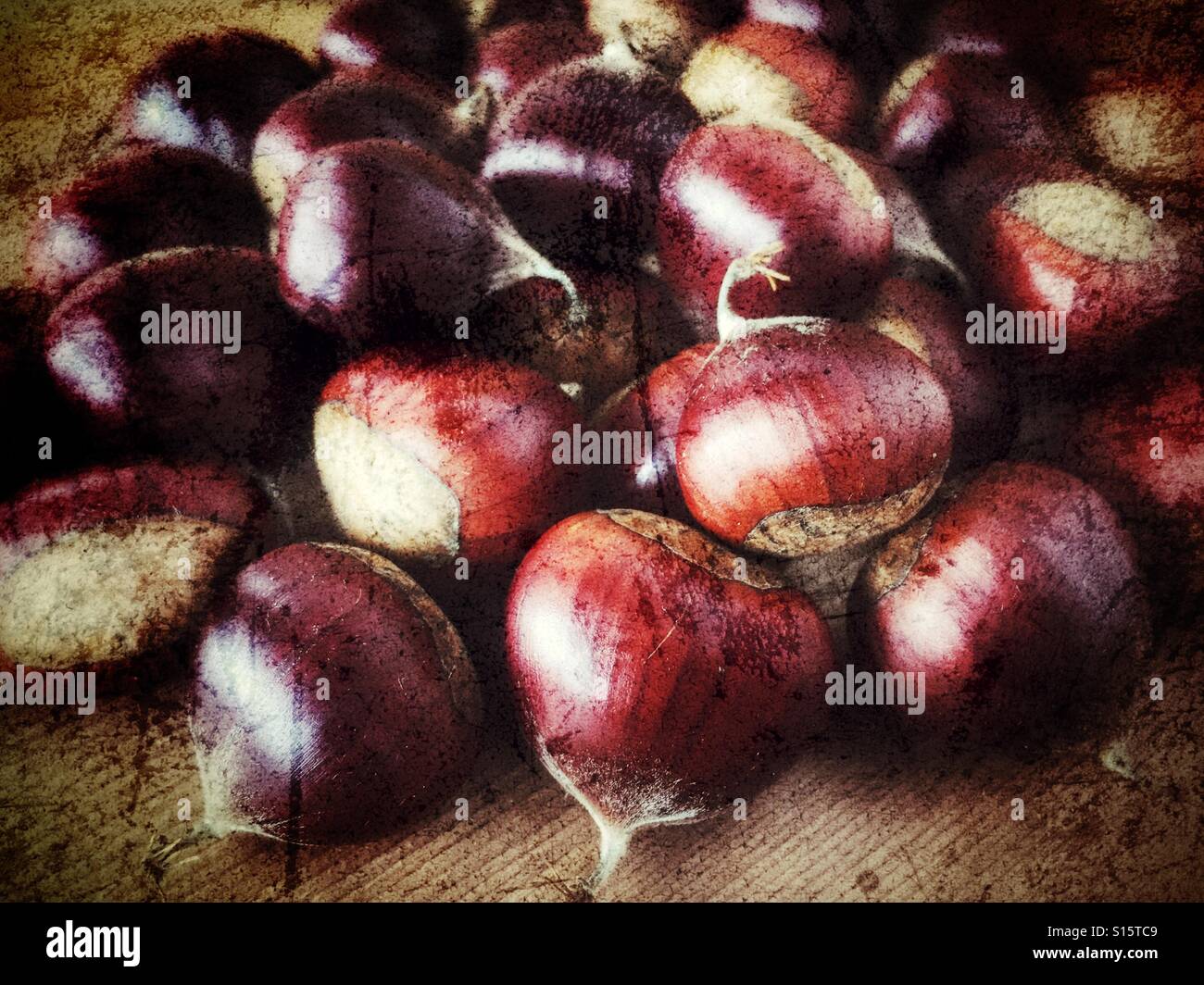 Close up view of shiny brown raw chestnuts on a wooden surface - Smartphone Captured Stock Image