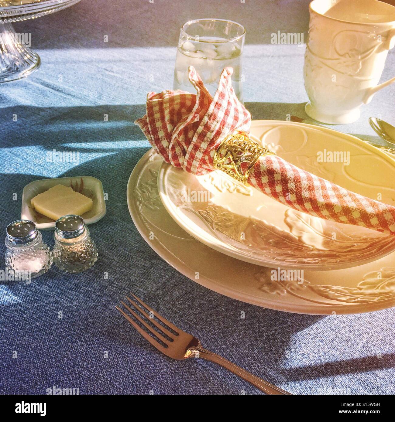 A beautiful tabletop place setting is bathed in sunlight ready for a guest. Stock Photo