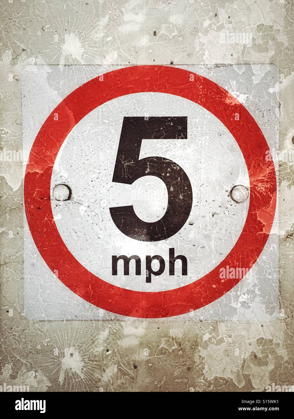 A grunge effect picture of a warning sign in a multi story car park - the speed limit is 5 Miles Per Hour. The red circle means this limit can be enforced by law. Photo Credit - © COLIN HOSKINS. - Smartphone Captured Stock Image