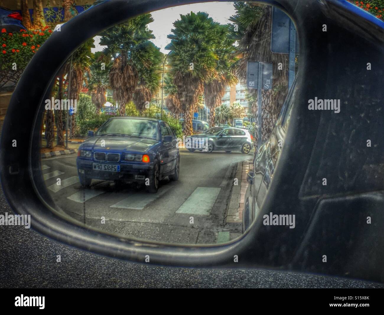 Car with indicator light on approaching a zebra crossing. Reflection in wing mirror - Smartphone Captured Stock Image