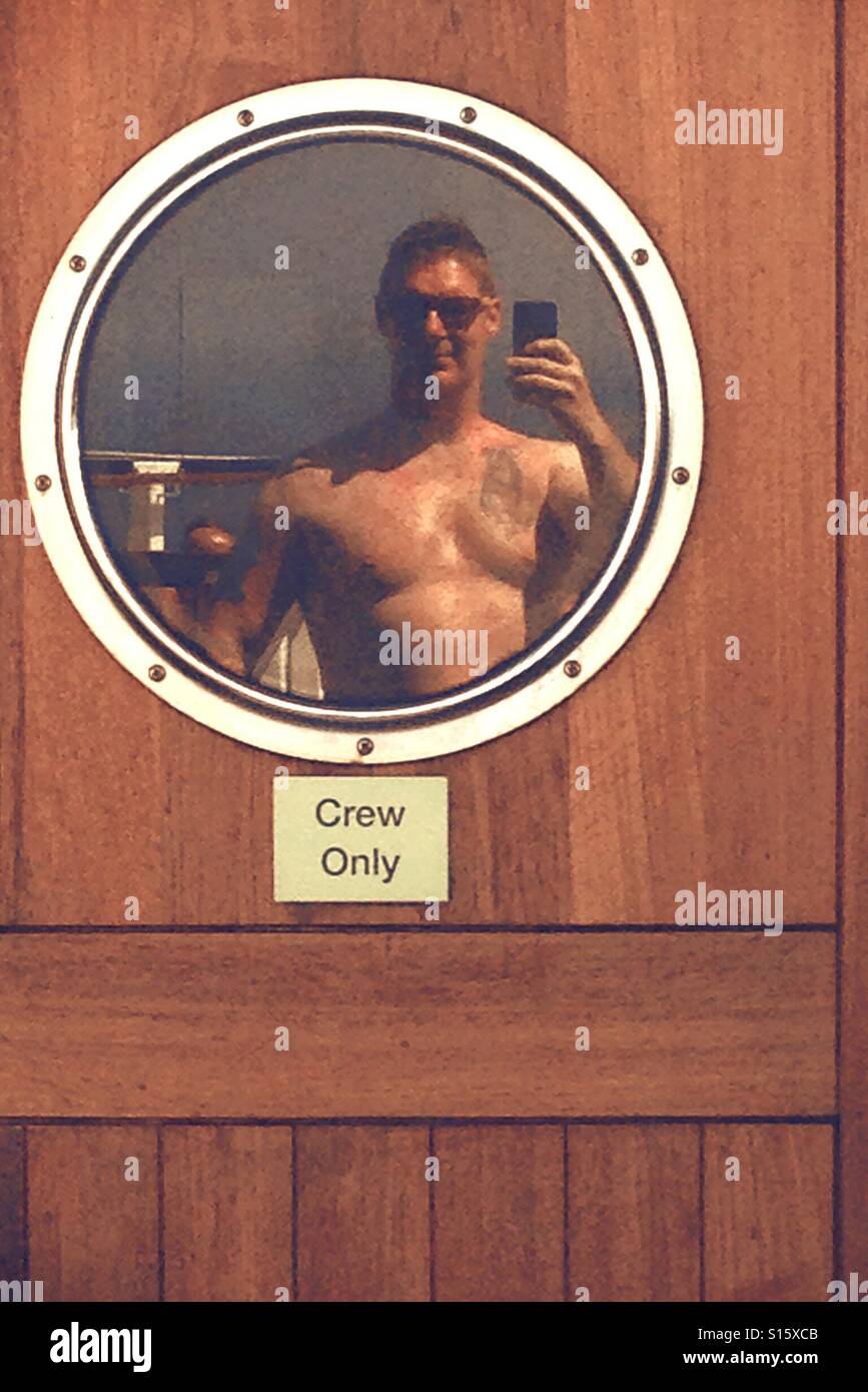 Man in sunglasses posing and taking a selfie in door window - Smartphone Captured Stock Image