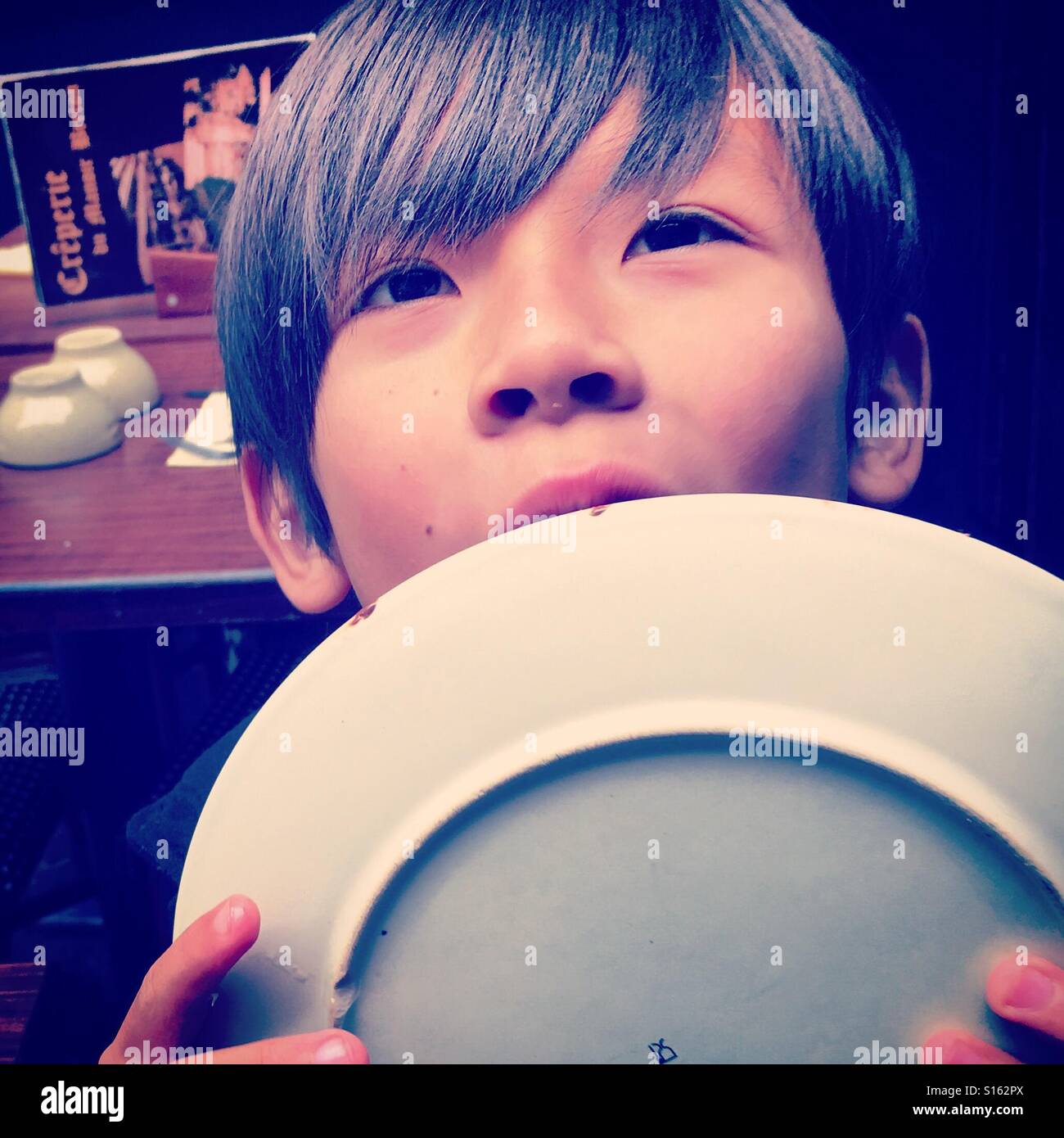 Child boy licking his plate Stock Photo