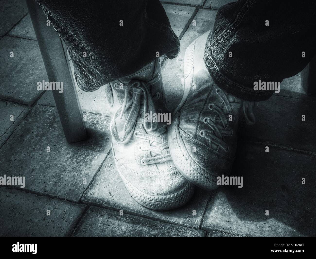 Sitting in a chair, feet under chair, close up - Smartphone Captured Stock Image