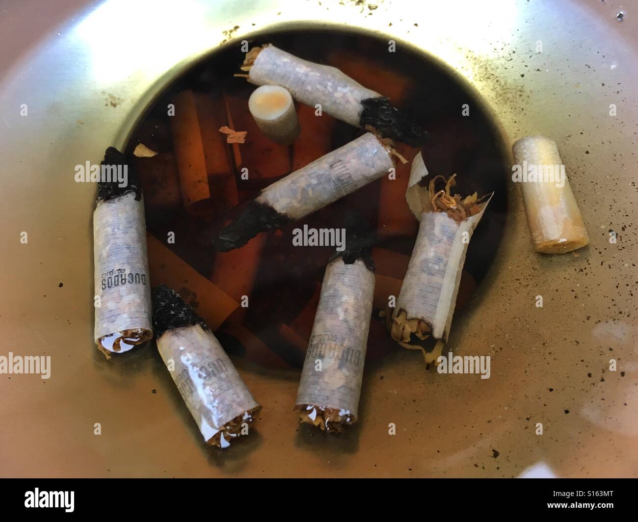 Cigarette butts floating in flooded ashtray Stock Photo
