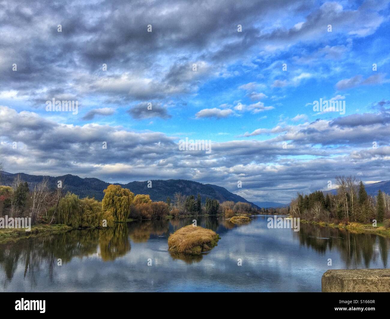 Autumn landscape in the Thompson/Okanagan with blue skies, clouds and colorful trees reflecting in the river - Smartphone Captured Stock Image