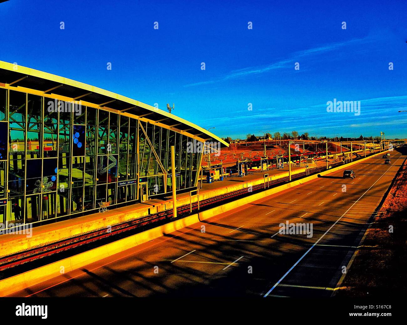 Light rail train station and track with late afternoon sun casting heavy shadows a cross Crowchild Trail - Smartphone Captured Stock Image