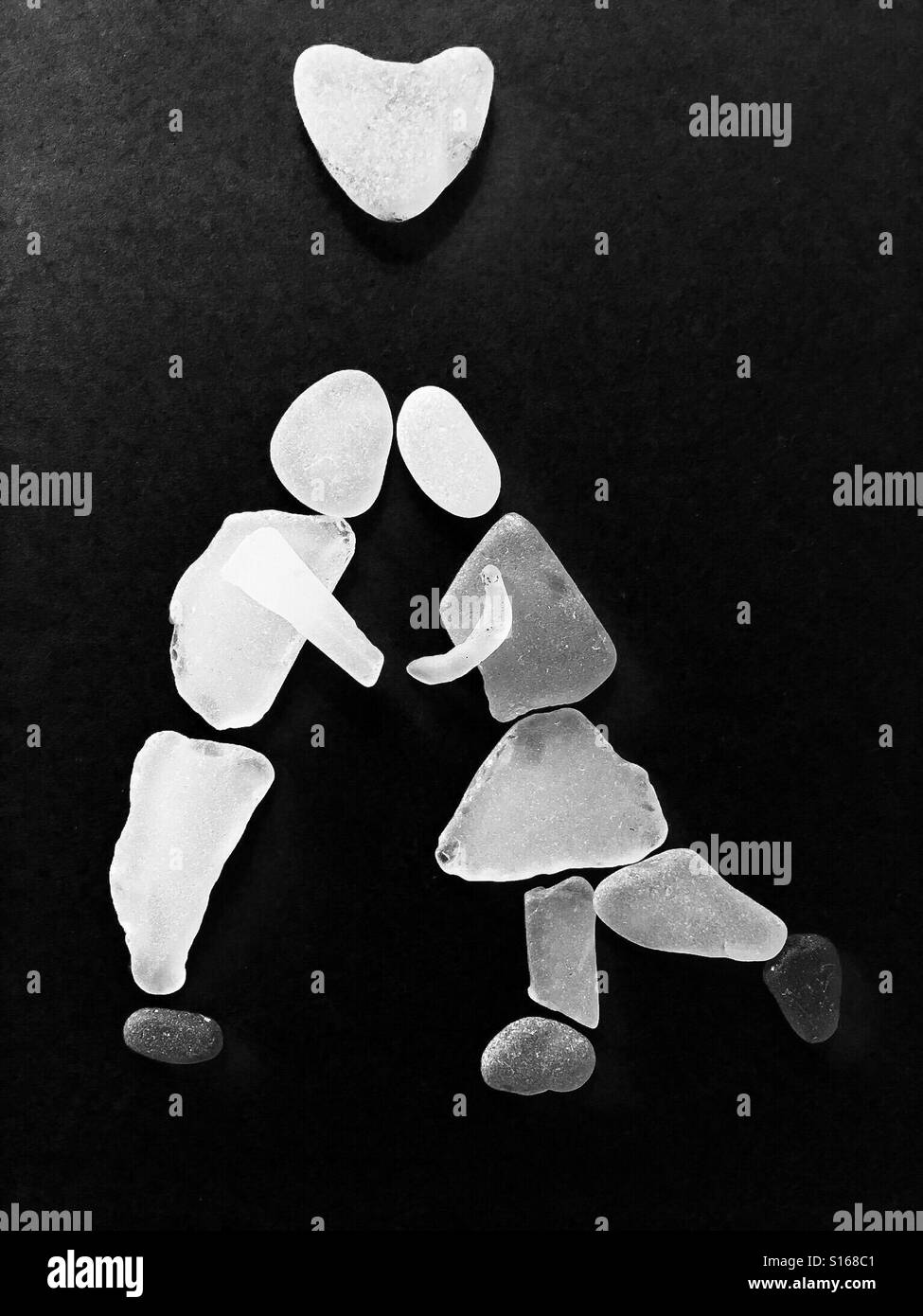 Sea glass figures in black and white - man and woman beneath a heart - Smartphone Captured Stock Image