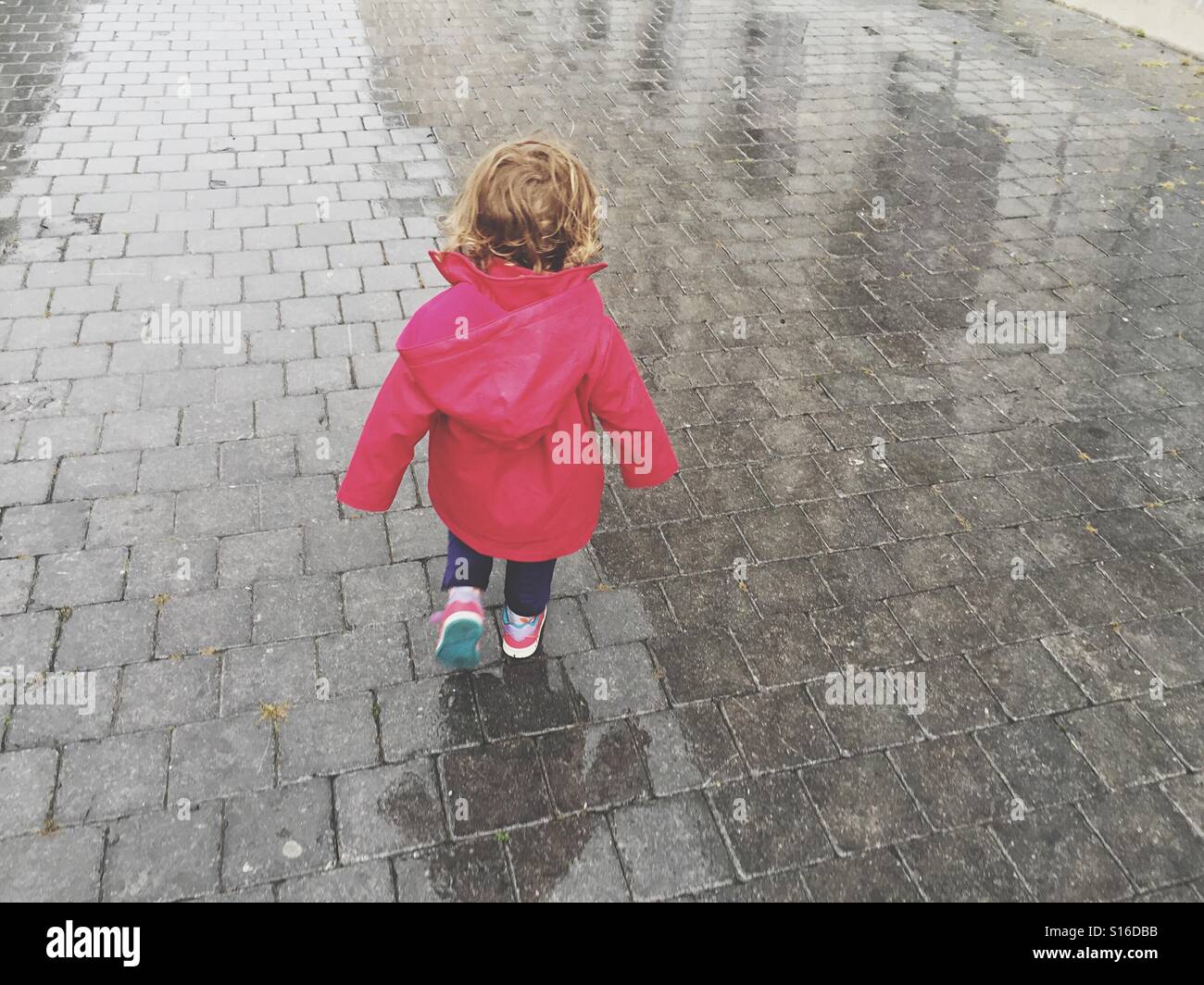 Toddler walking on the street, rainy day Stock Photo