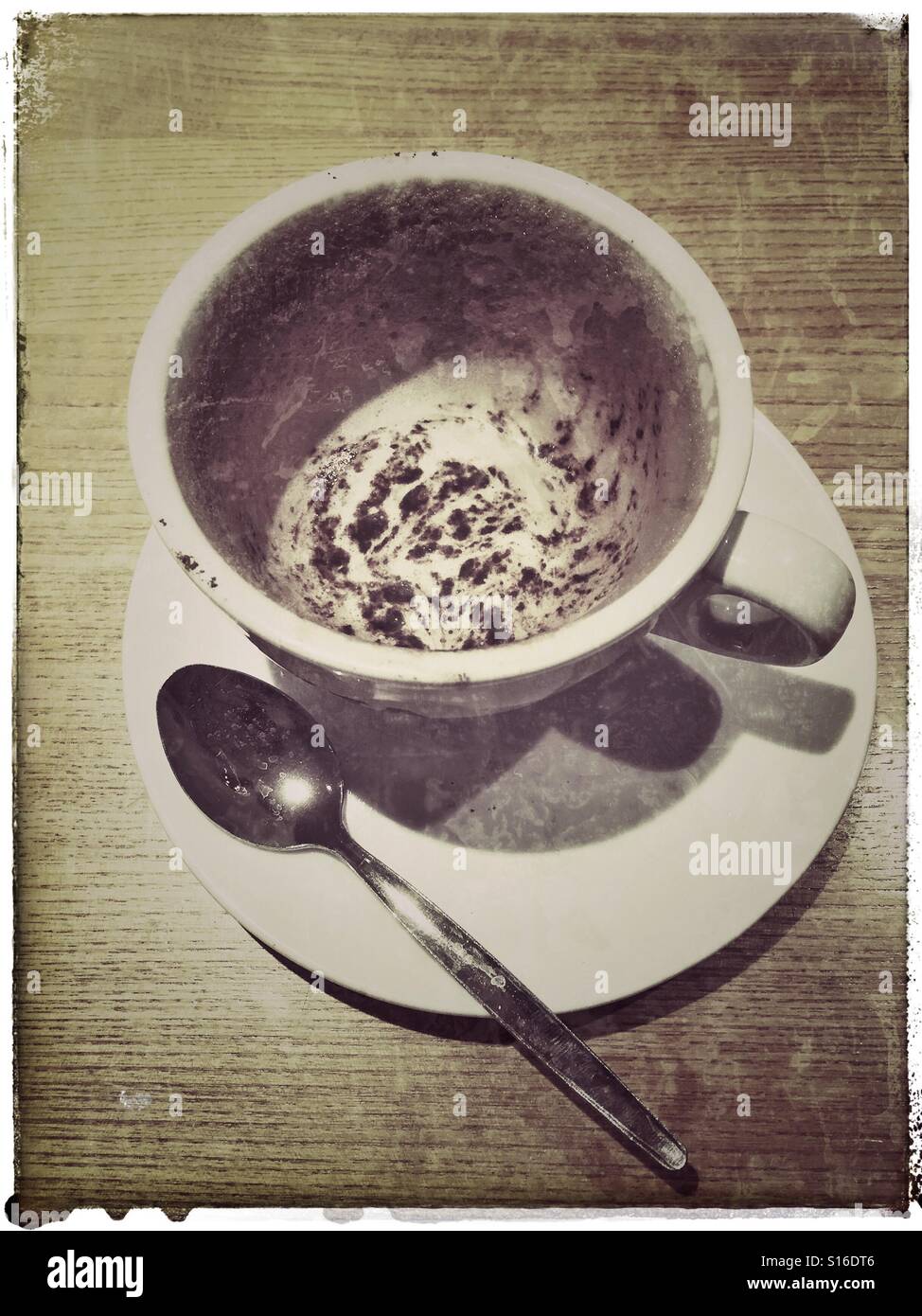 An overhead picture of an empty cup of Cappuccino Coffee drink. A dirty spoon lies on the saucer, next to the cup. Photo Credit - © COLIN HOSKINS. - Smartphone Captured Stock Image