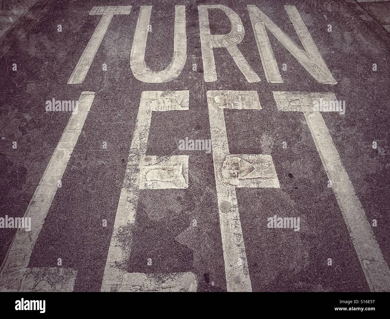 'TURN LEFT' The words painted on the Tarmac, instructing road users to only Turn Left at the road junction they are approaching. Photo Credit - © COLUN HOSKINS. - Smartphone Captured Stock Image