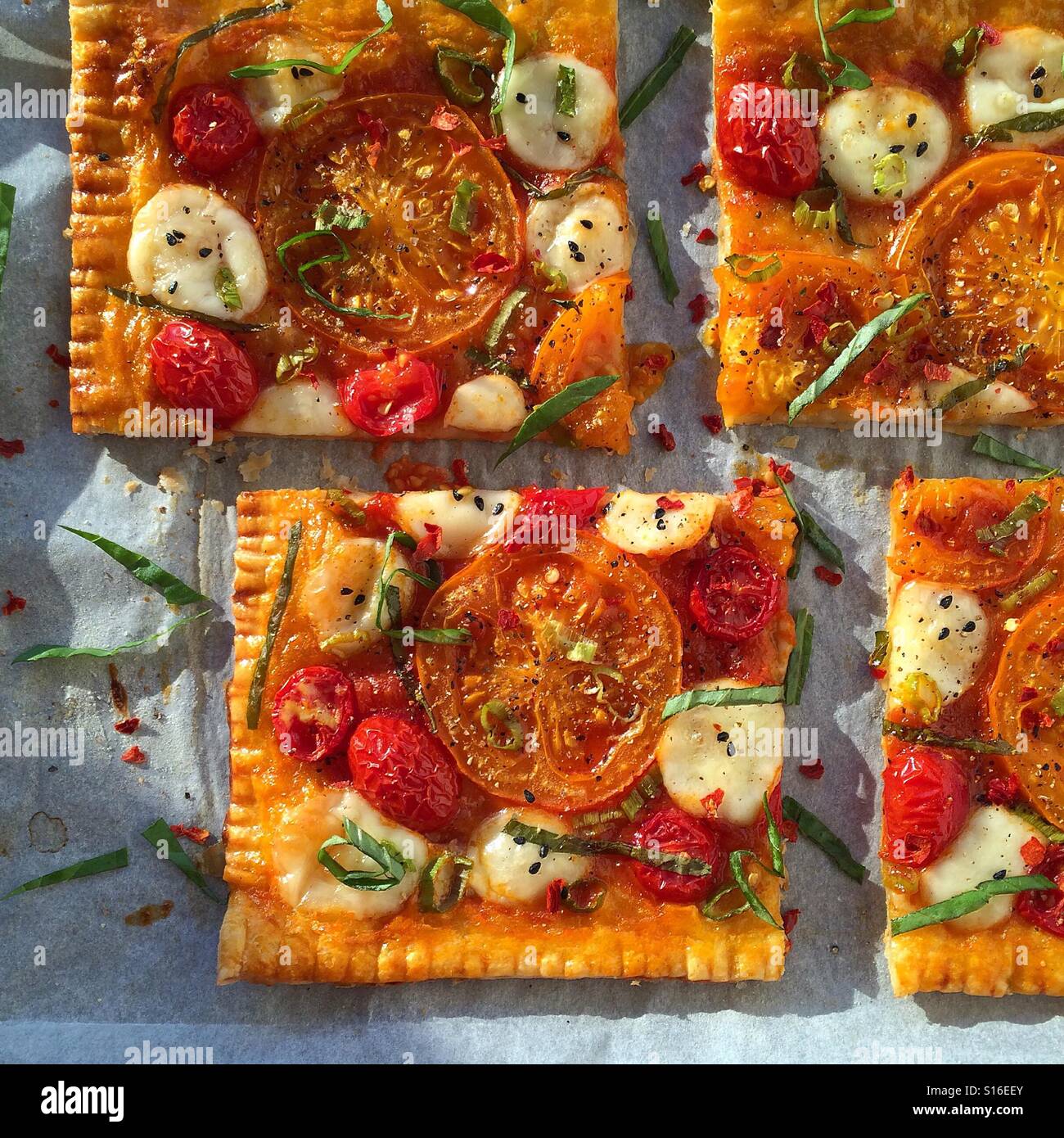 Tomato puff pastry tart with fresh mozzarella and basil Stock Photo Alamy