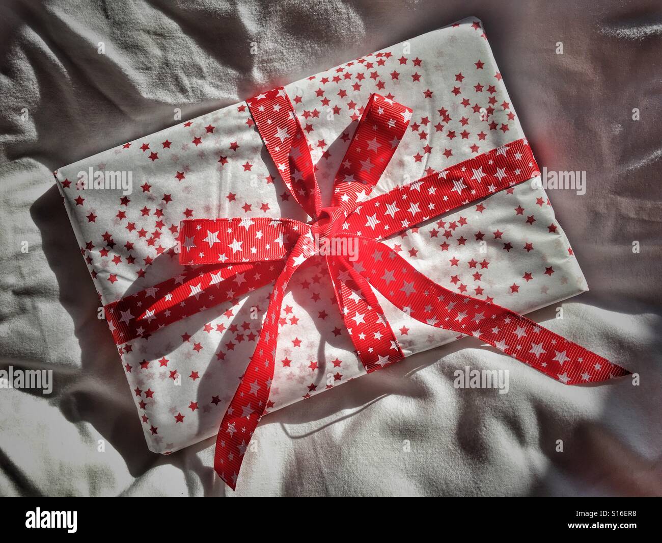 Beautifully wrapped present, with a red ribbon bow - Smartphone Captured Stock Image