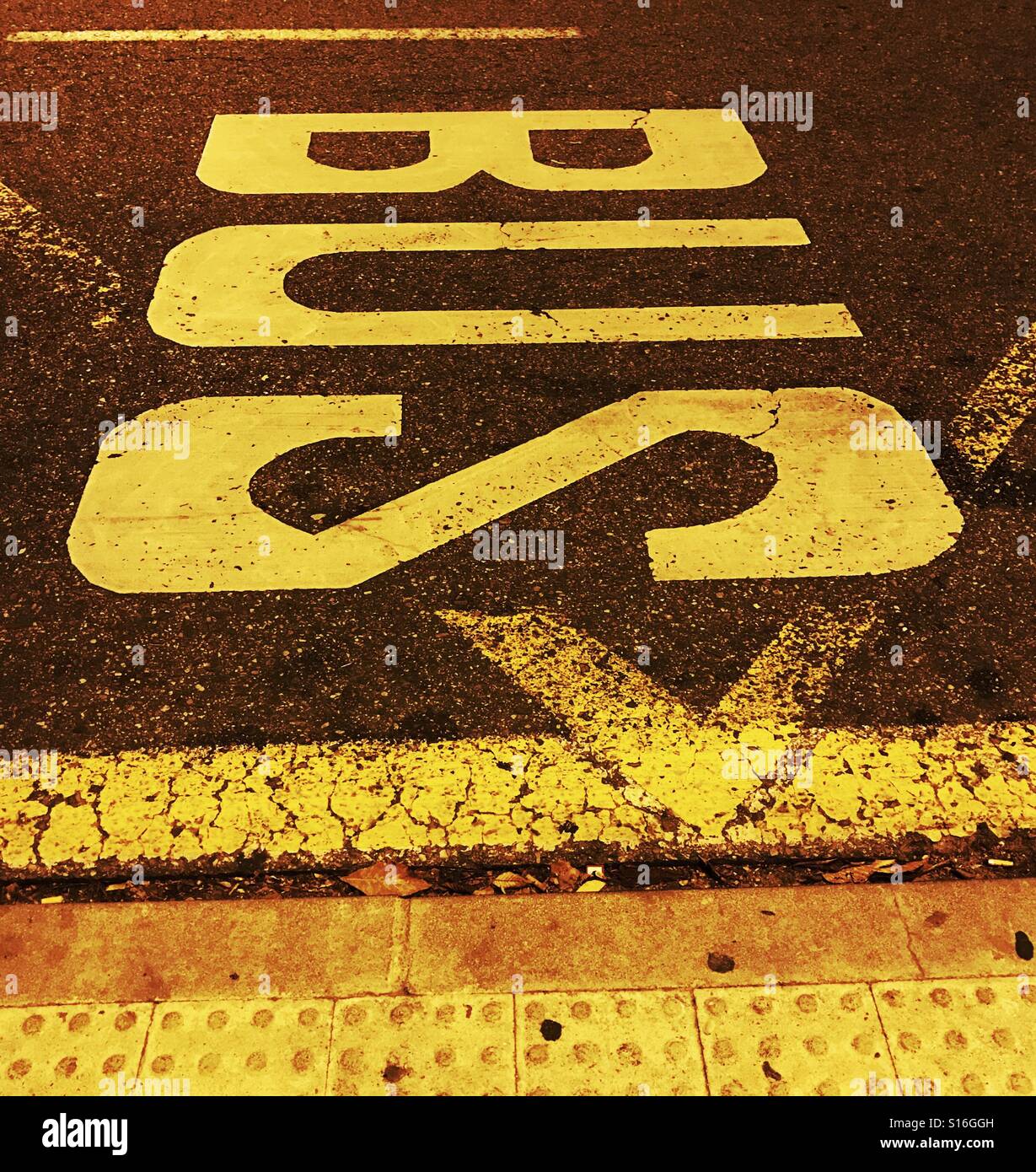 Markings on the road tarmac in bright yellow fluorescent paint to indicate bus stop Stock Photo