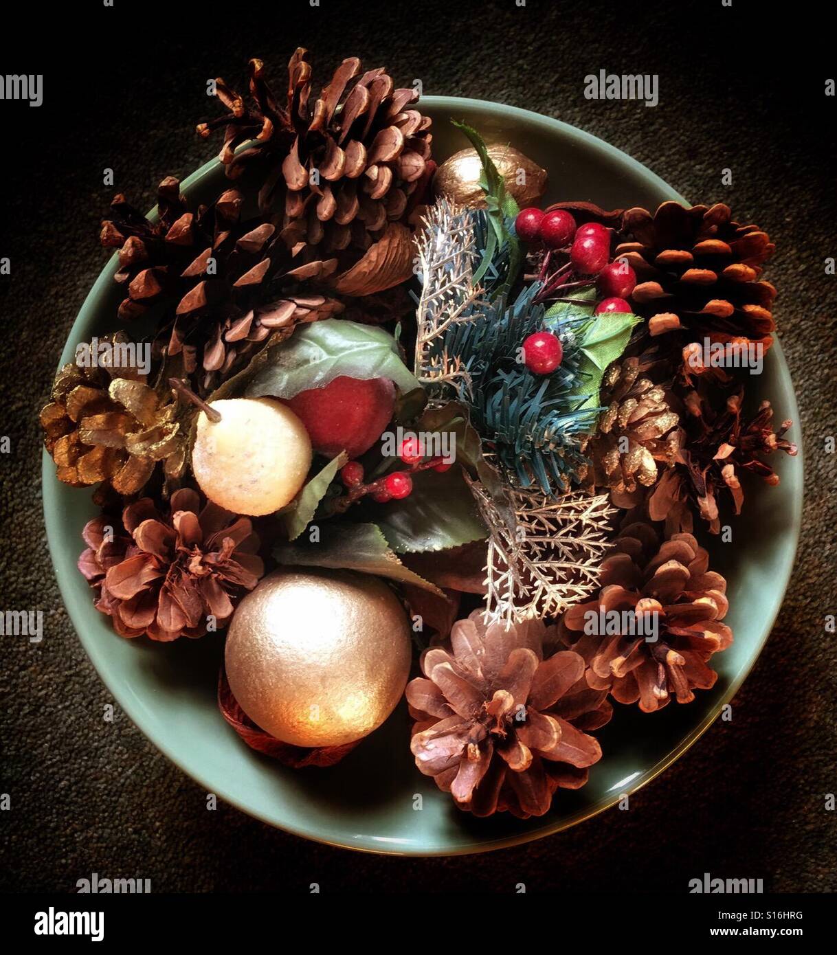 Looking down on a bowl of festive, winter decorations, with berries, cones and leaves - Smartphone Captured Stock Image
