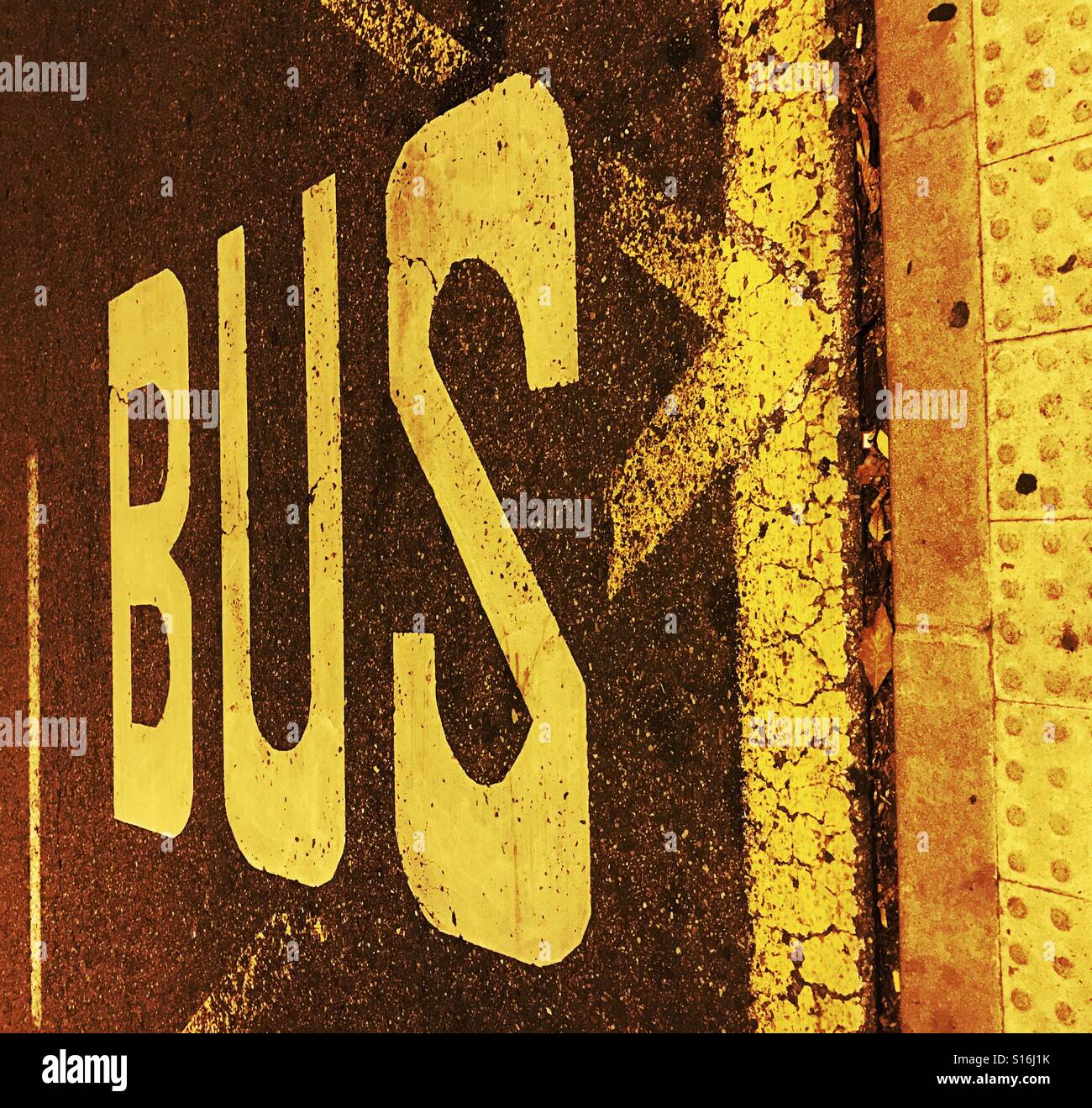 Markings on the road tarmac in bright yellow flourescent paint to indicate bus stop Stock Photo