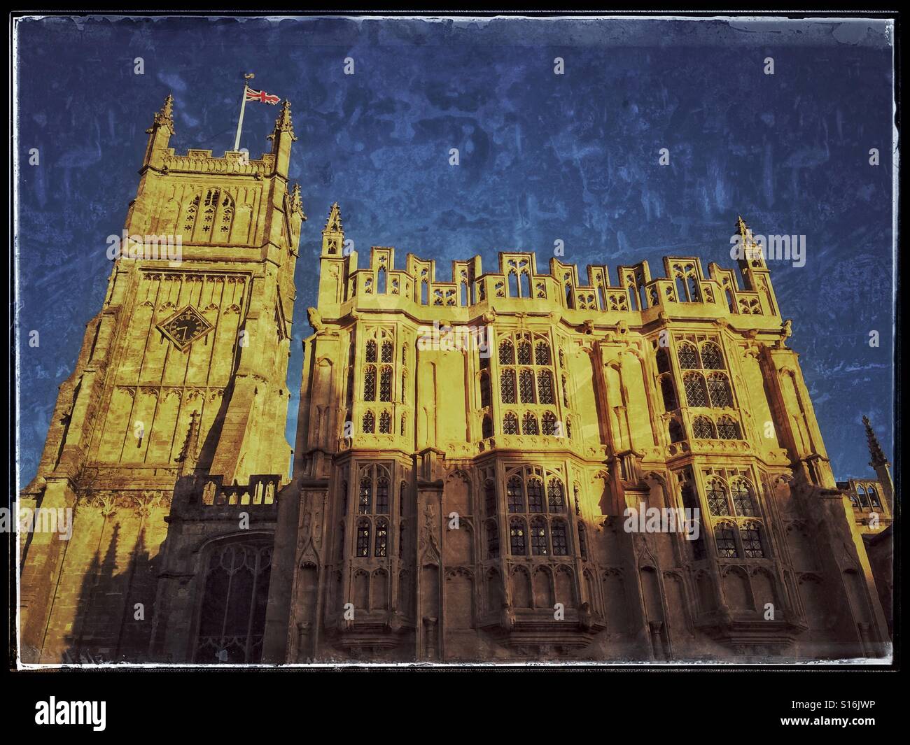 A grunge effect image of the exterior view of St. John Baptist Parish Church in Cirencester, Gloucestershire, England. The Union Jack flies from the 15th Century Tower. Photo Credit - © COLIN HOSKINS. - Smartphone Captured Stock Image