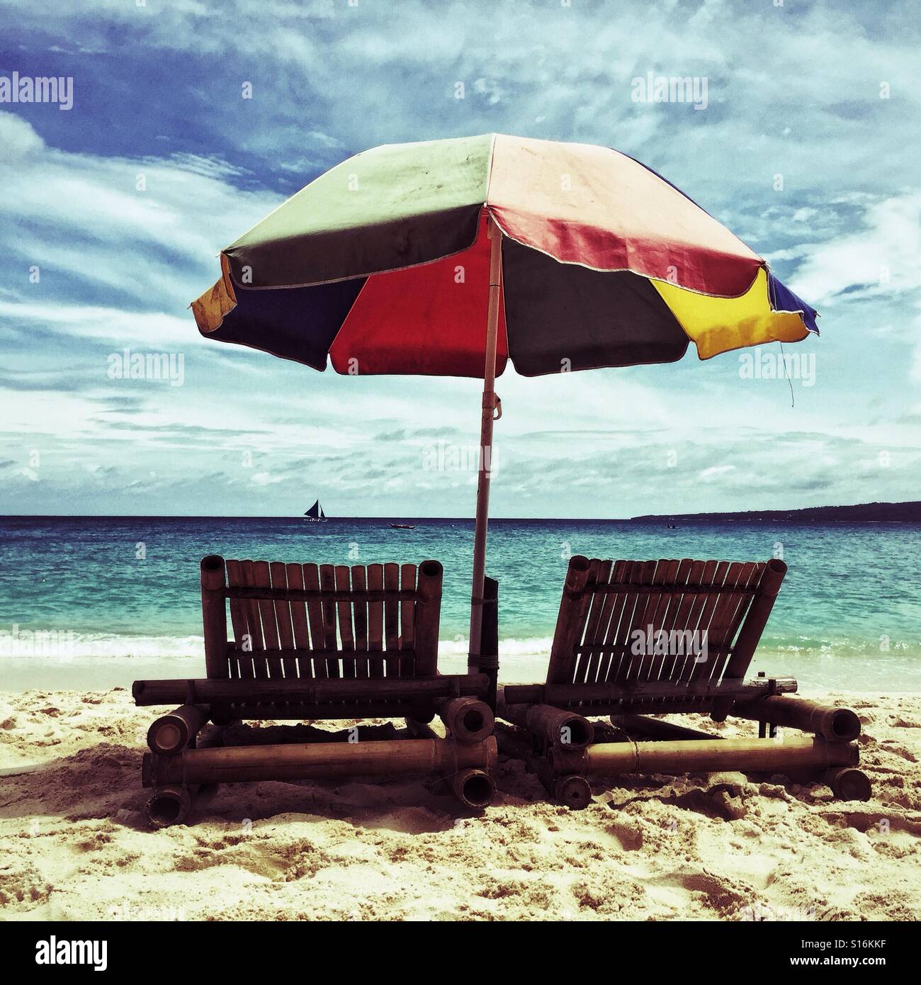 bamboo chairs under beach umbrella on a sandy Puka Beach, Boracay island, Philippines - Smartphone Captured Stock Image