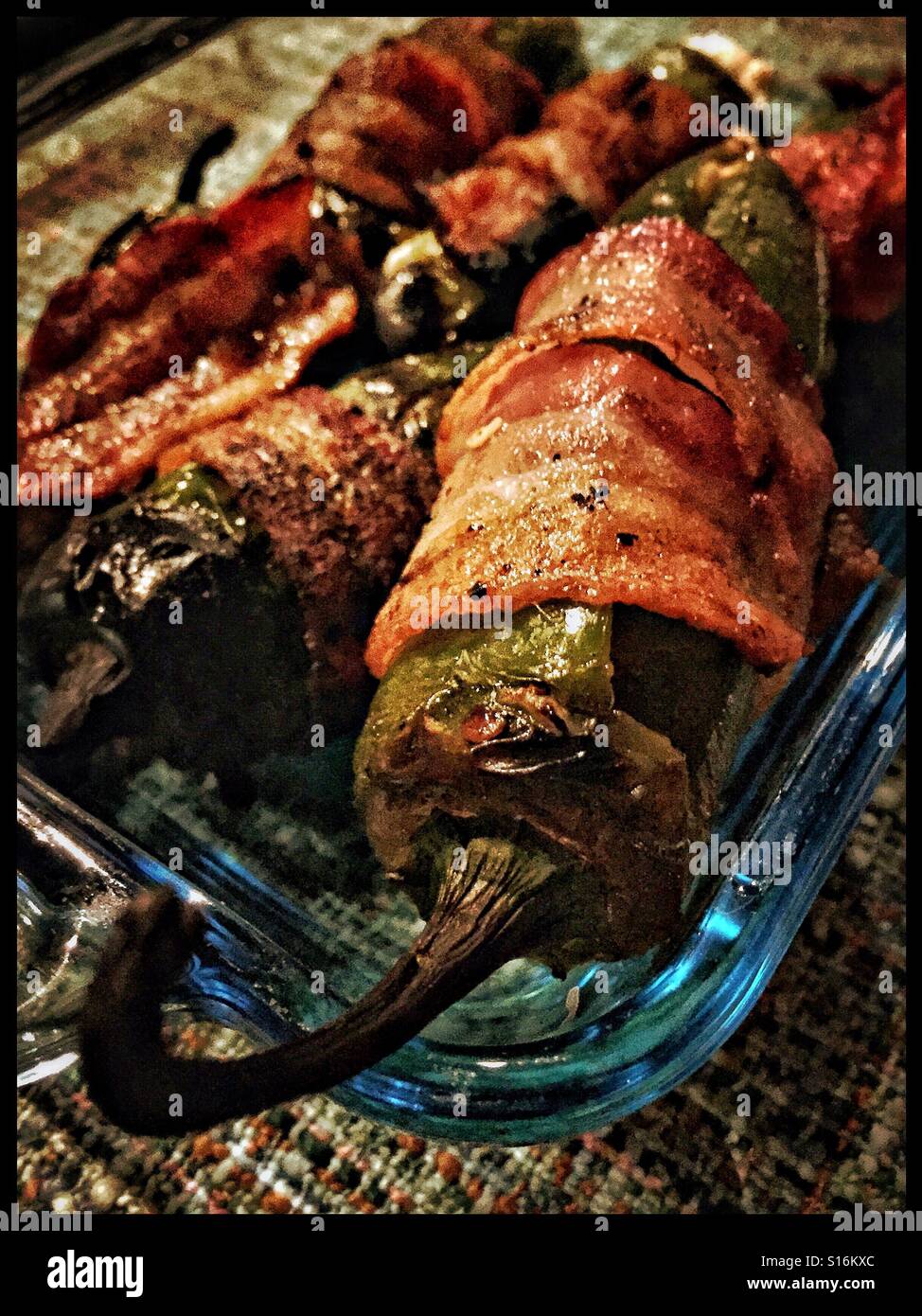Bacon wrapped, goat cheese stuffed jalapeños hot off the grill. Stock Photo