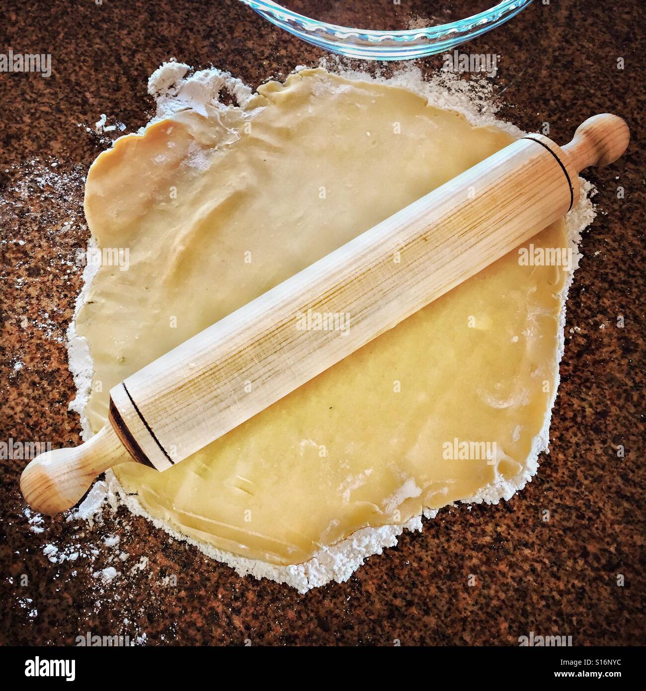 Homemade pie dough is being flattened by a rolling pin. Stock Photo
