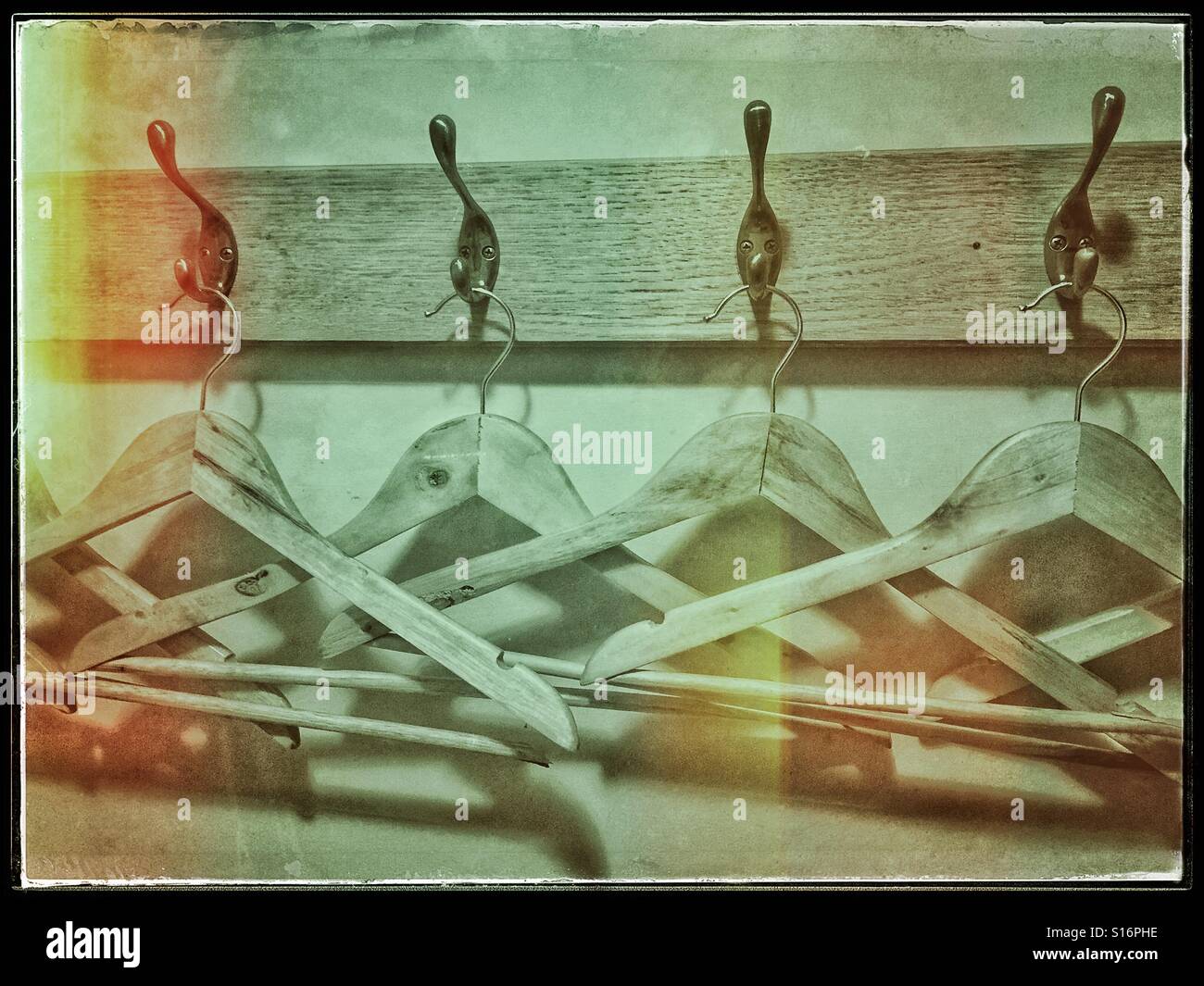A retro effect image of a row of wooden coat hangers and pegs awaiting use. Why are they so close together? Where are the jackets & coats? Photo Credit - © COLIN HOSKINS. Stock Photo