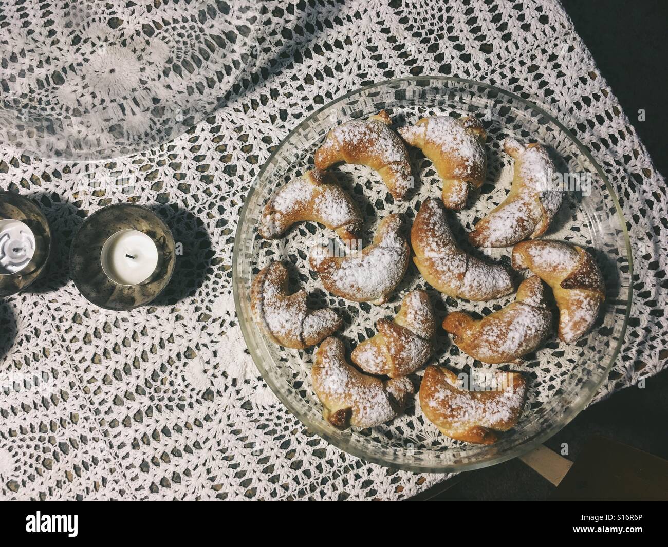 Christmas cookies on a glass circle plate with candles on a rustic table clothes Stock Photo