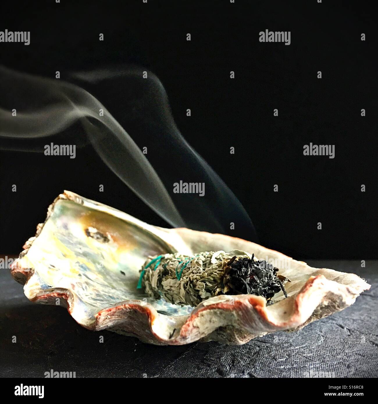 Sage smudge stick burning in an abalone shell. Stock Photo