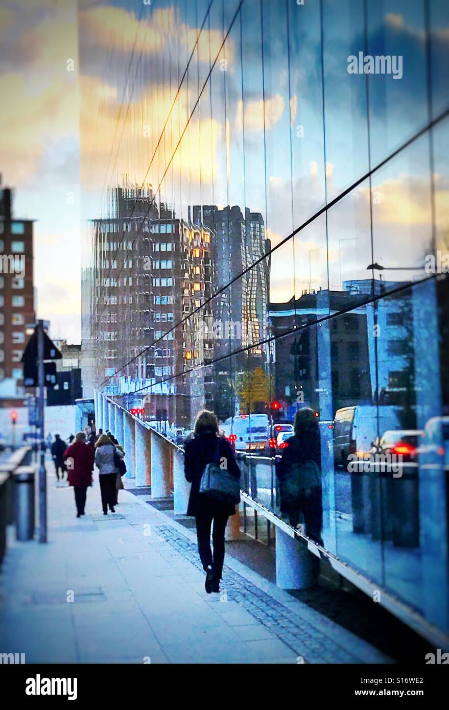 People heading for Southwark underground station in the late early afternoon, reflected in a glass sided office building Stock Photo