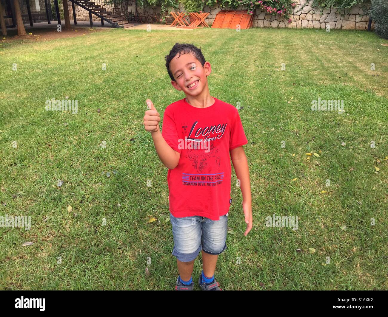 Happy boy thumbs up after long play on green field - Smartphone Captured Stock Image