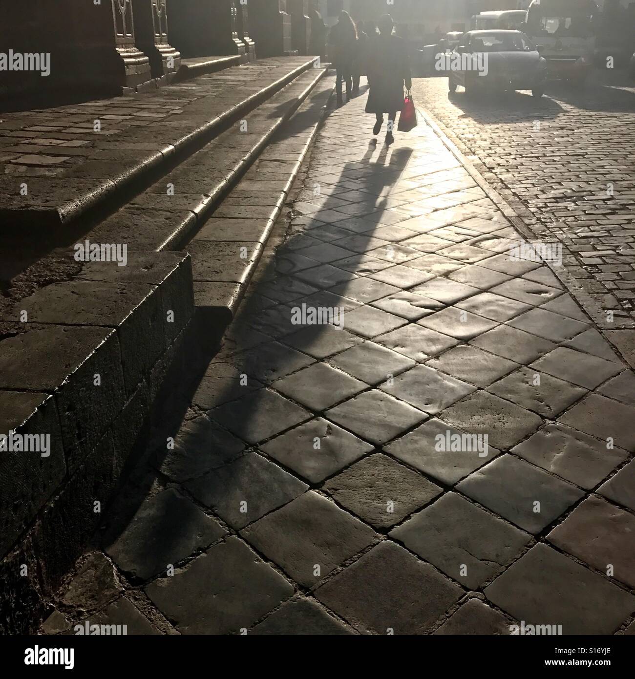 Woman with a shopping bag casts a long shadow Stock Photo
