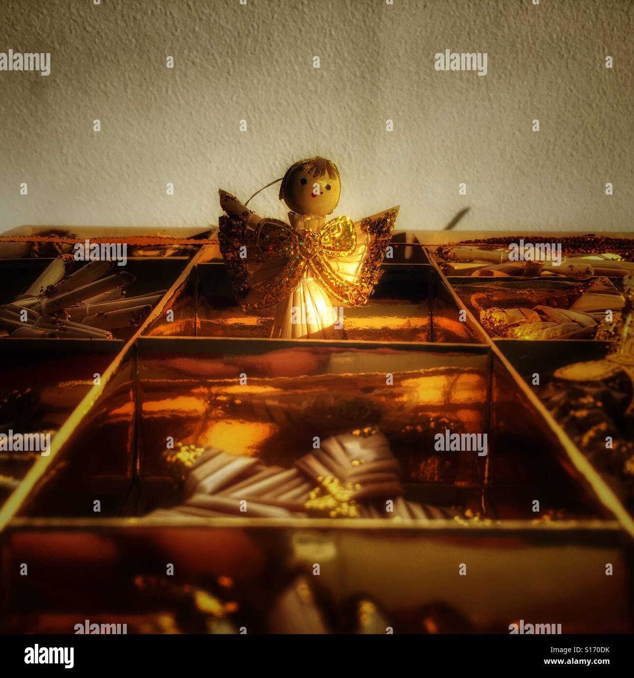 Box of Christmas decorations, focus on a straw angel decorated with gold glitter. - Smartphone Captured Stock Image