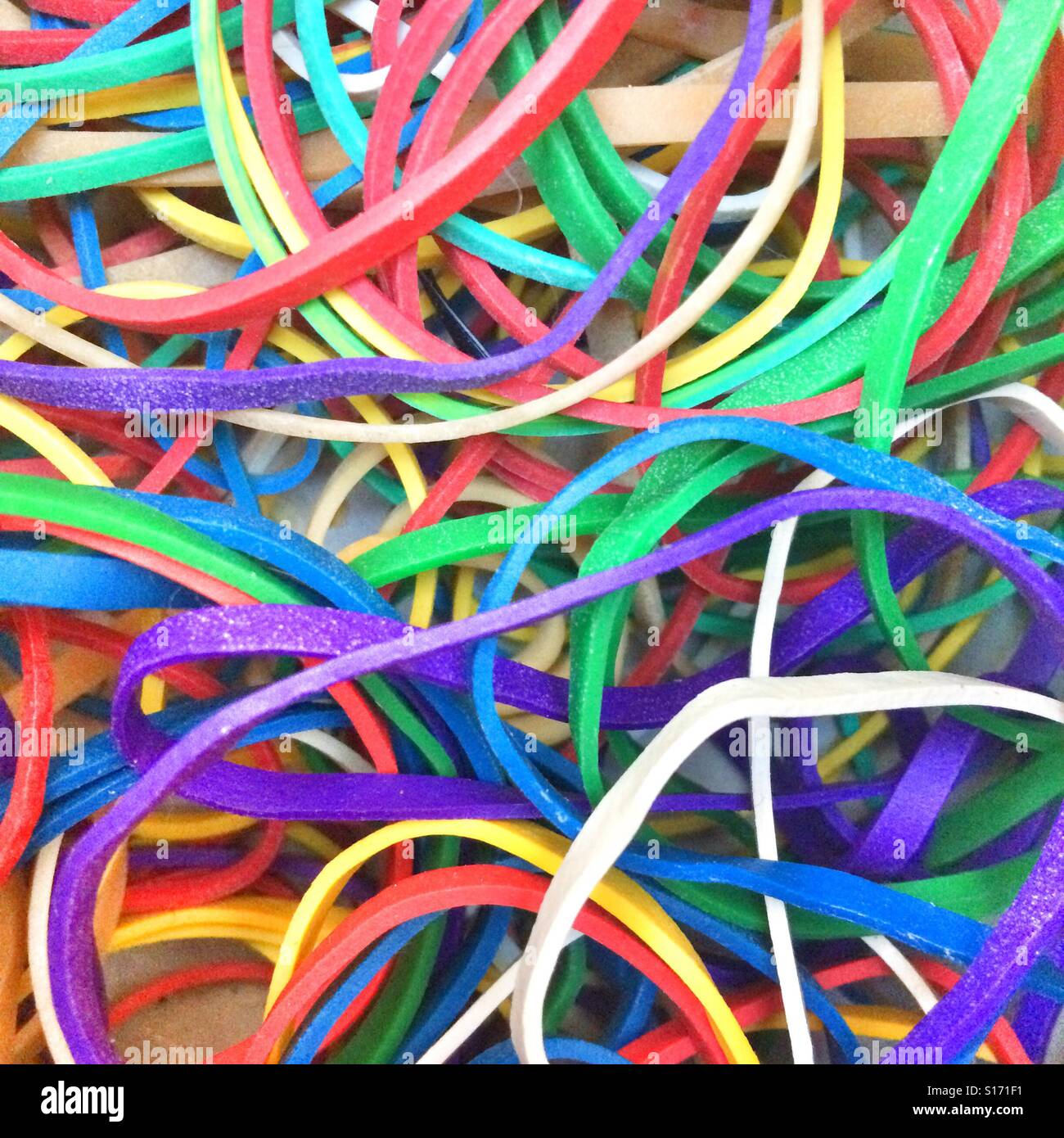 Colorful assortment of rubber bands spread out on a wooden surface showcasing vibrant hues and varied sizes - Smartphone Captured Stock Image
