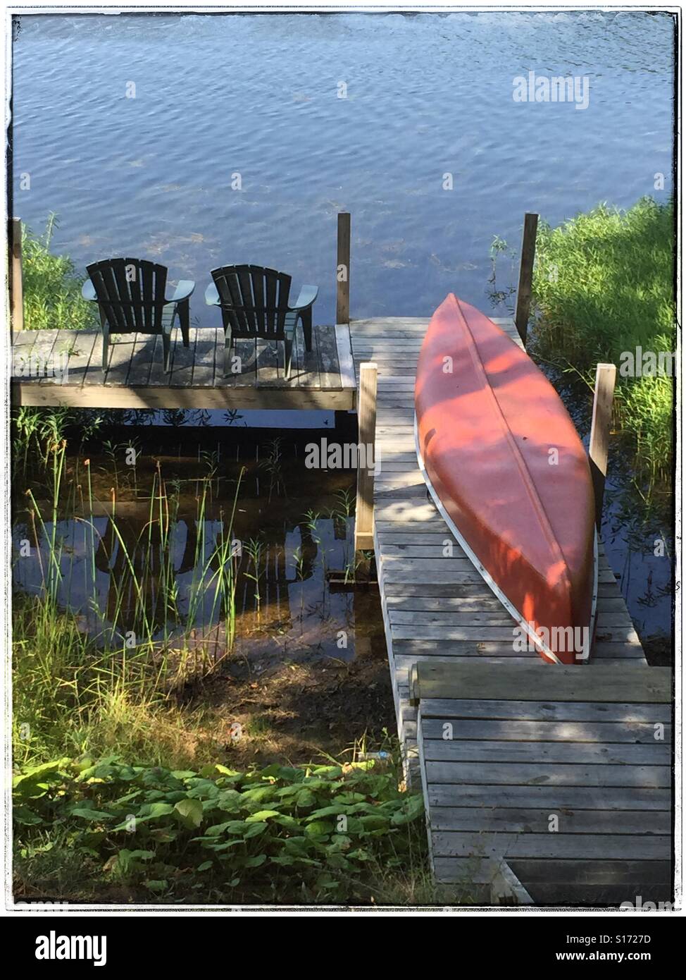 Adirondack chairs and canoe on dock on a lake in the Adirondacks, New